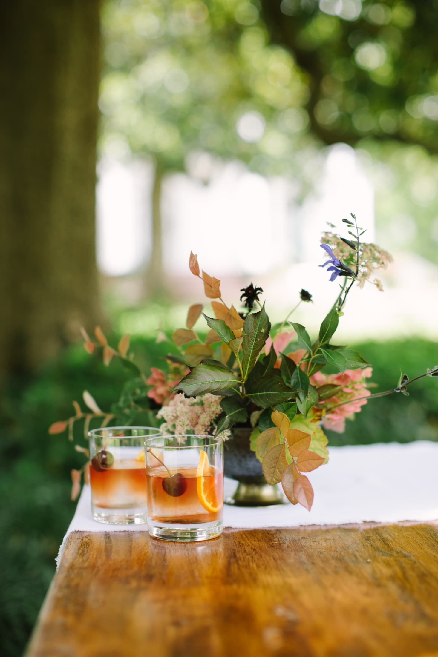Old fashioneds beside a floral arrangement