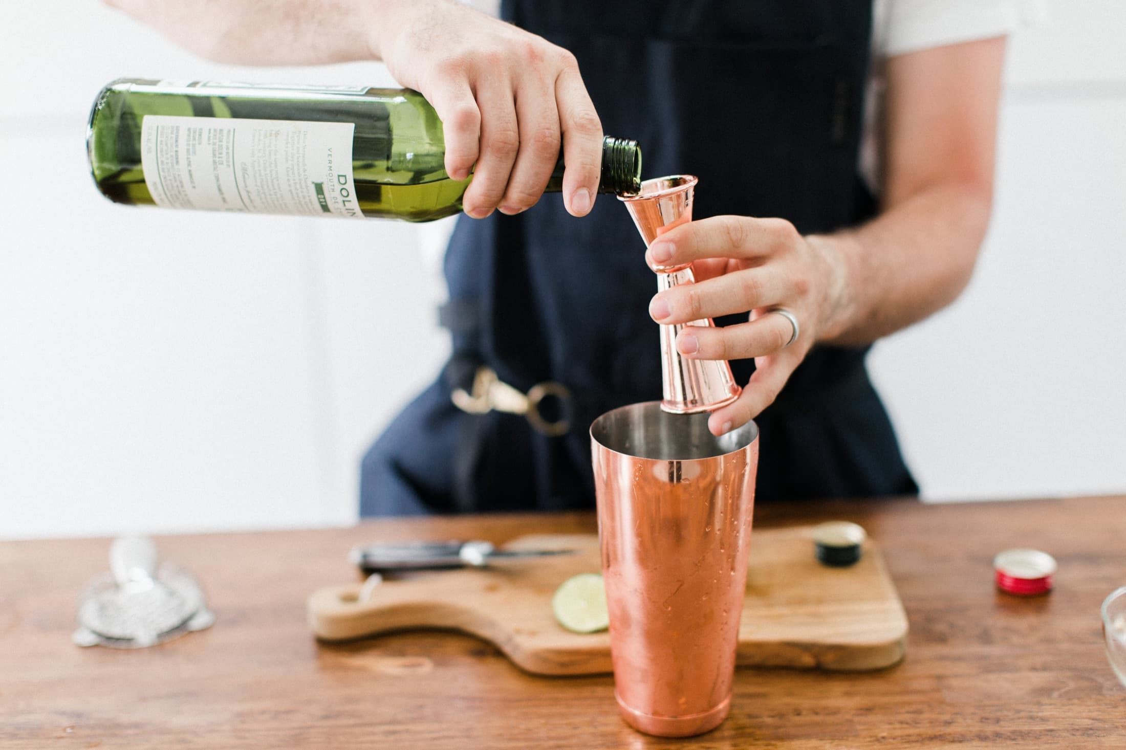 Bartender measuring vermouth into a copper shaker